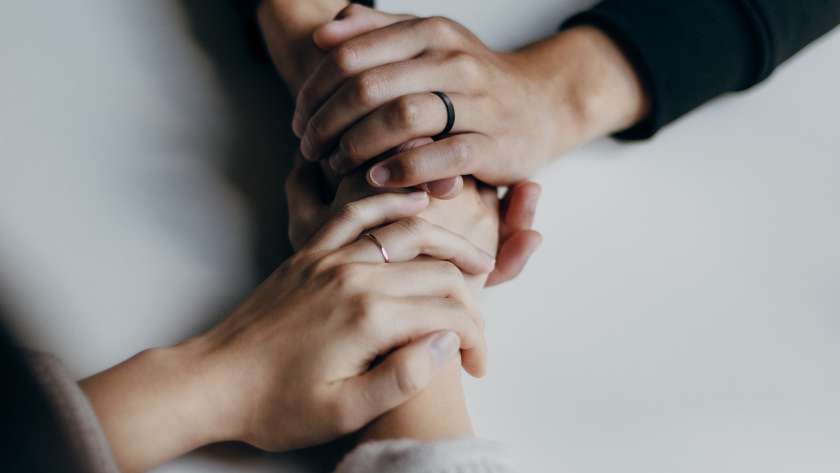 Colleagues hold hands over a table
