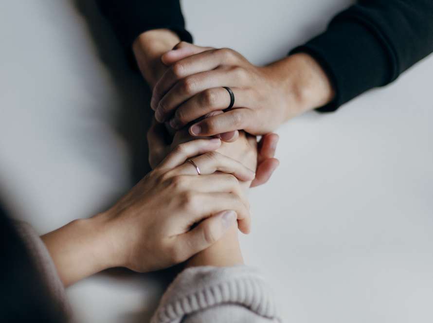 Colleagues hold hands over a table