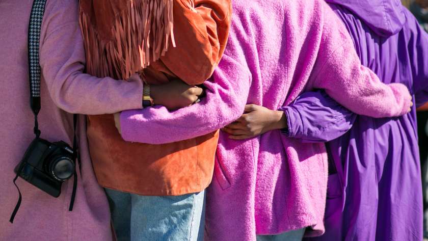 group of women supporting each other by embracing in a line